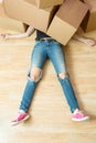 Image of woman in jeans lying under cardboard boxes Royalty Free Stock Photo