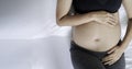 Image of A woman pregnant reclining on bed and touching or caressing her belly with hands. Royalty Free Stock Photo