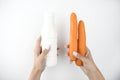 Image of woman`s hands holding yogurt in plastic bottle in one hand and two fresh carrots in another on  white background Royalty Free Stock Photo