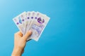 Image woman`s hands which holds British pounds in her hands isolated over blue studio background