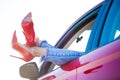 Image of woman`s legs in red shoes sticking out of red car window Royalty Free Stock Photo