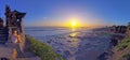 Image of woman sitting on temple wall watching sunset on cliff coast of Indonesian island Bali Royalty Free Stock Photo