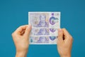 Image womans hands which holds British pounds in her hands isolated over blue studio background