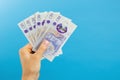 Image womans hands which holds British pounds in her hands isolated over blue studio background