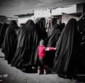 Image of women in black hijabs and a single child inside the Al-Hol camp in black and white.