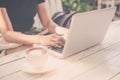 Image of women working on her computer laptop in coffee shop with cappuccino coffee on white table. Female hands typing on noteboo Royalty Free Stock Photo