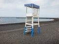 Image of wooden life rescue coast guard tower on the empty beach with black volcanic sand