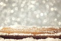 Image of wooden old table and december fresh snow on top. in front of glitter background. selective focus