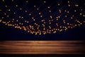 Image of wooden table in front of abstract blurred city golden garland lights background. Royalty Free Stock Photo