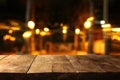 Image of wooden table in front of abstract blurred restaurant lights background Royalty Free Stock Photo