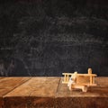 Image of wooden toy airplane over wooden table against chalk blackboard background. retro style image Royalty Free Stock Photo