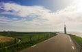 Dike in the Netherlands with a small white firetower on the road during sunny day. Royalty Free Stock Photo