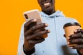 Image of african american guy holding cellphone and takeway coffee cup Royalty Free Stock Photo