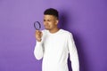 Image of young african-american male student looking for something with magnifying glass, squinting as cant see