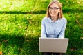 Image of a young amazing lady, sitting in a park, using a laptop computer, sits on a green lawn. Royalty Free Stock Photo