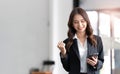 Image of a young Asian businesswoman standing using mobile phone at the office. Royalty Free Stock Photo