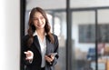 Image of a young Asian businesswoman standing using mobile phone at the office. Royalty Free Stock Photo