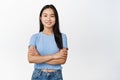 Image of young asian female model cross arms on chest, looking confident and smiling at camera, standing in casual Royalty Free Stock Photo