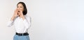 Image of young asian woman calling for someone, shouting loud and searching around, standing against white background Royalty Free Stock Photo