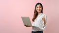 Image of young Asian woman holding laptop and give a thumbs up sign, pink isolated background Royalty Free Stock Photo
