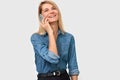 Image of young beautiful blonde woman in denim shirt smiling and talking on smart phone to her friend, looking cheerful and happy Royalty Free Stock Photo