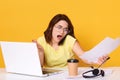 Image of young beautiful Caucasian astonished lady with dark hair using laptop and phone, having business conversation with her Royalty Free Stock Photo