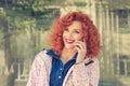 Curly redhead woman outdoors talking by mobile phone Royalty Free Stock Photo