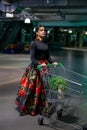 Image of a young beautiful woman in a bright skirt with a supermarket trolley Royalty Free Stock Photo