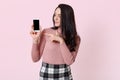 Image of young beautiful woman holding smart phone and showing at its blank screen isolated over pink background, female with long Royalty Free Stock Photo