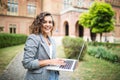 Image of young beautiful woman student walking in the park using mobile phone holding laptop computer Royalty Free Stock Photo