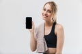 Image of young blond woman 20s dressed in sportswear with towel over neck using smartphone during workout in gym Royalty Free Stock Photo