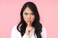 Image of young brunette asian woman frowning and holding finger on lips Royalty Free Stock Photo