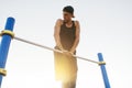 Image of young Caucasian muscular male doing pull ups exercises on horizontal bar outdoors. Athletic runner training hard at sunny Royalty Free Stock Photo