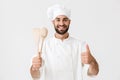 Image of young chief man in cook uniform smiling while holding wooden kitchen utensils Royalty Free Stock Photo