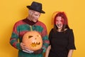 Image of young couple celebrate Halloween, male in striped sweater and black hat, has knives instead of fingers, female in black Royalty Free Stock Photo