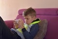 Image of young cute boy playing games on mobile phone lounging on sofa
