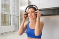 Image of young fitness girl, wearing blue tracksuit, puts on wireless headphones to workout with music, does yoga at Royalty Free Stock Photo