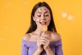 Image of young funny woman with stickers on face liking lollipop