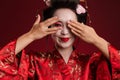 Image of young geisha woman in traditional kimono covering her eyes with hands Royalty Free Stock Photo