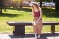 Image of young girl charges mobile phone via USB outdoors, female sitting on bench with solar panel in town park. Public charging Royalty Free Stock Photo