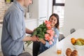 Image of young happy caucasian people, man gives a flowers to his woman at home. Women`s day, Mother`s day