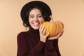 Cheery brunette woman holding pumpkin