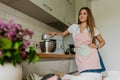 Image of young happy lady standing in kitchen while cooking fish. Looking at camera. Royalty Free Stock Photo