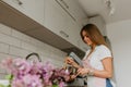 Image of young happy lady standing in kitchen while cooking fish. Looking at camera. Royalty Free Stock Photo
