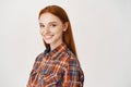 Image of young happy redhead woman with pale skin and no make-up, smiling at camera, standing over white background