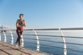 Image of young healthy sportswoman jogging near seaside. Fitness girl running and working out on pier Royalty Free Stock Photo