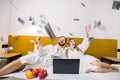 Image of a young lovely couple of newlyweds throw money up, while sitting on the bed in hotel room, using laptop and Royalty Free Stock Photo