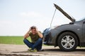 Image of young man sitting next to broken car with open hood Royalty Free Stock Photo