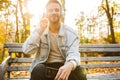 Image of young man wearing headphones sitting on bench in autumn park Royalty Free Stock Photo