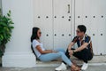 Image of a young man and woman dressed informally talking while sitting outdoors